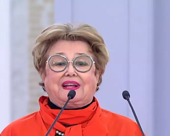 Марина Неёлова в очках и оранжевой блузе выступает у микрофона